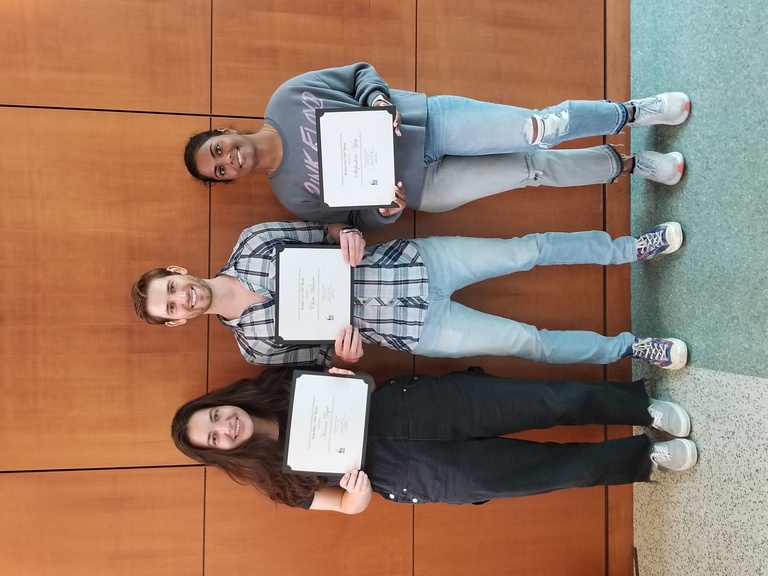 Three people pose with certificates